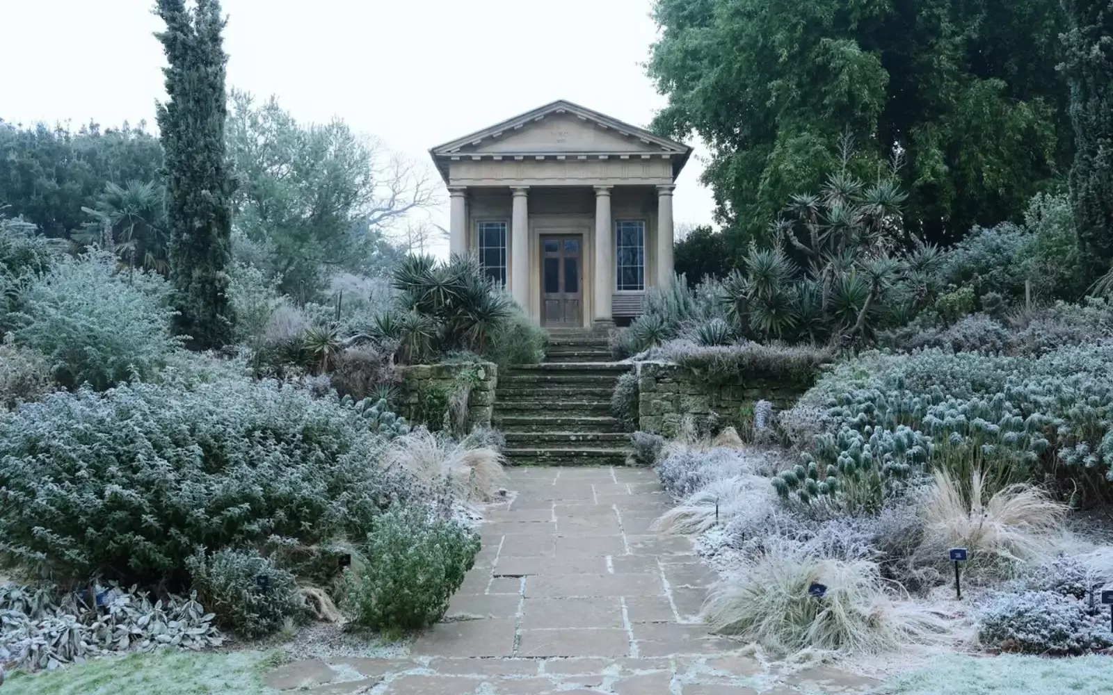 Jardin couvert de givre au petit matin, allée menant à un pavillon